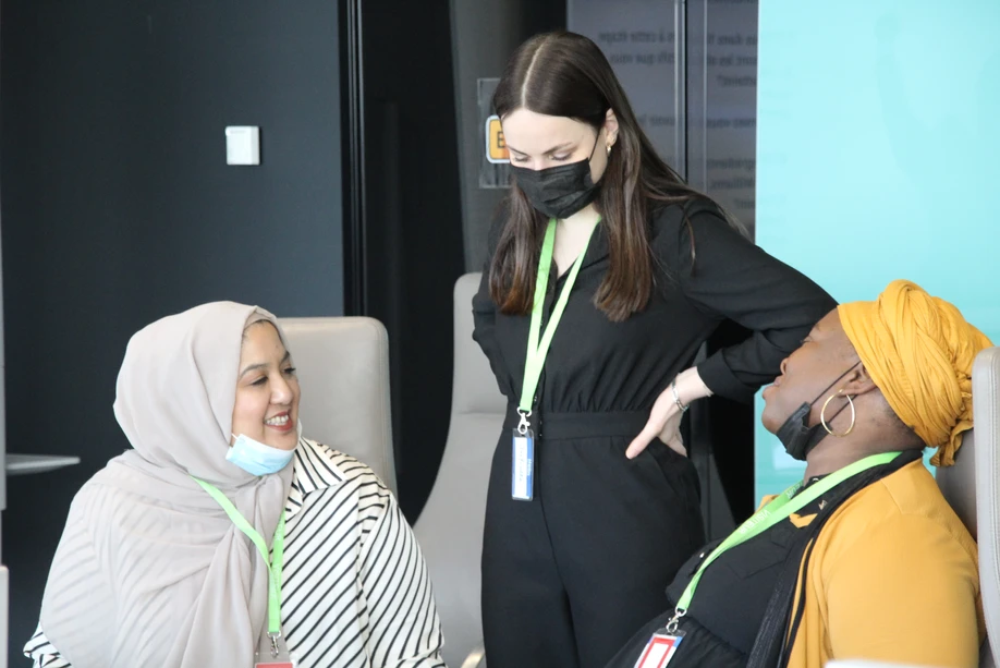 Une cheffe souriante en tenue blanche dresse une table élégante en extérieur avec des amuse-bouches, des plats colorés et des compositions florales, illustrant une expérience traiteur printanière raffinée et conviviale.