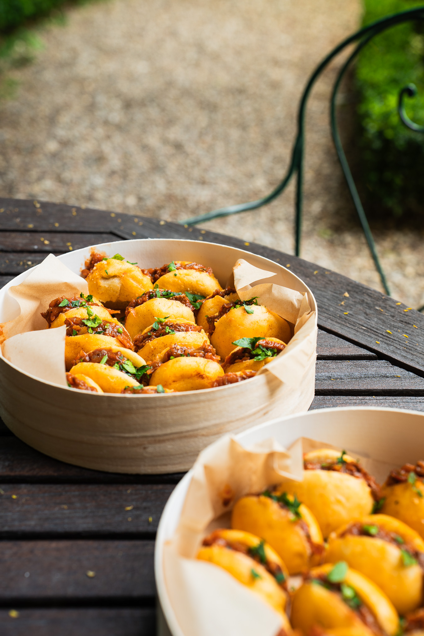 Une pince dépose délicatement une fleur comestible sur des bouchées raffinées avec un glaçage jaune brillant, présentées sur une assiette blanche dans un style gastronomique élégant.