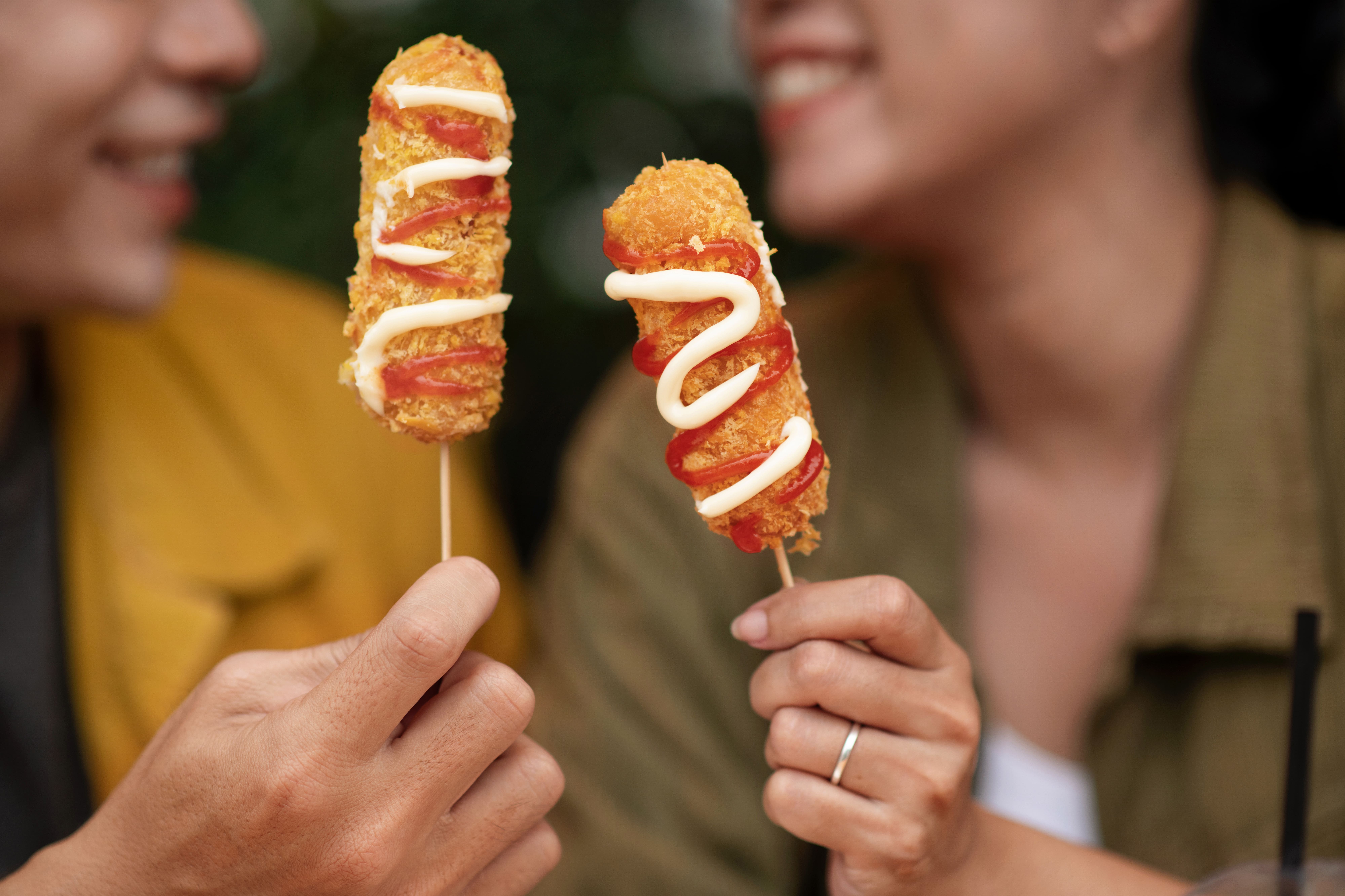 Smiling customers holding Donny's Dogs corn dogs.