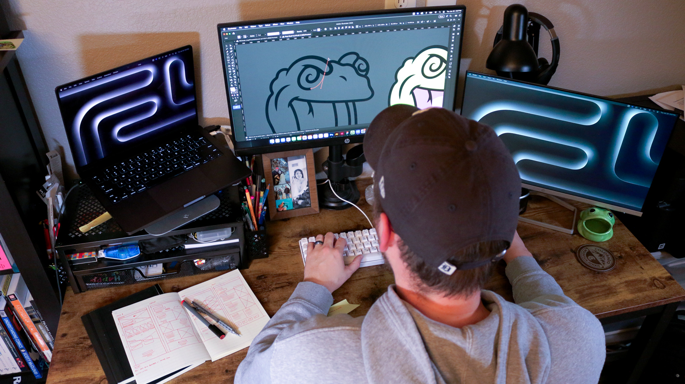 Designer's workspace with sketchbook, laptop, and tools for client retainer work.