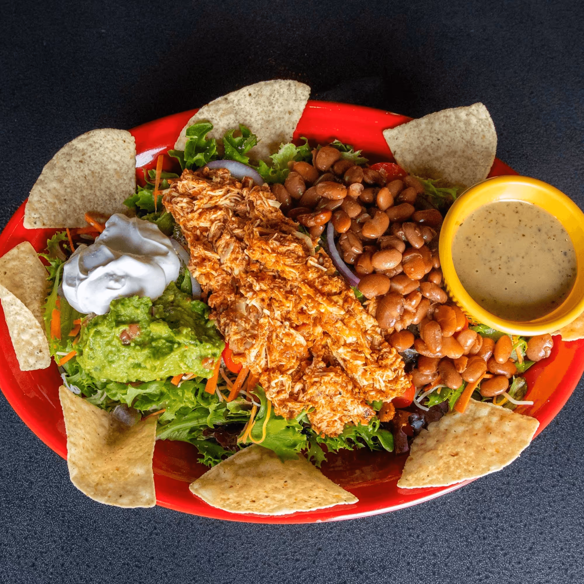 A plate of food with a variety of ingredients including beans, lettuce, and salsa.