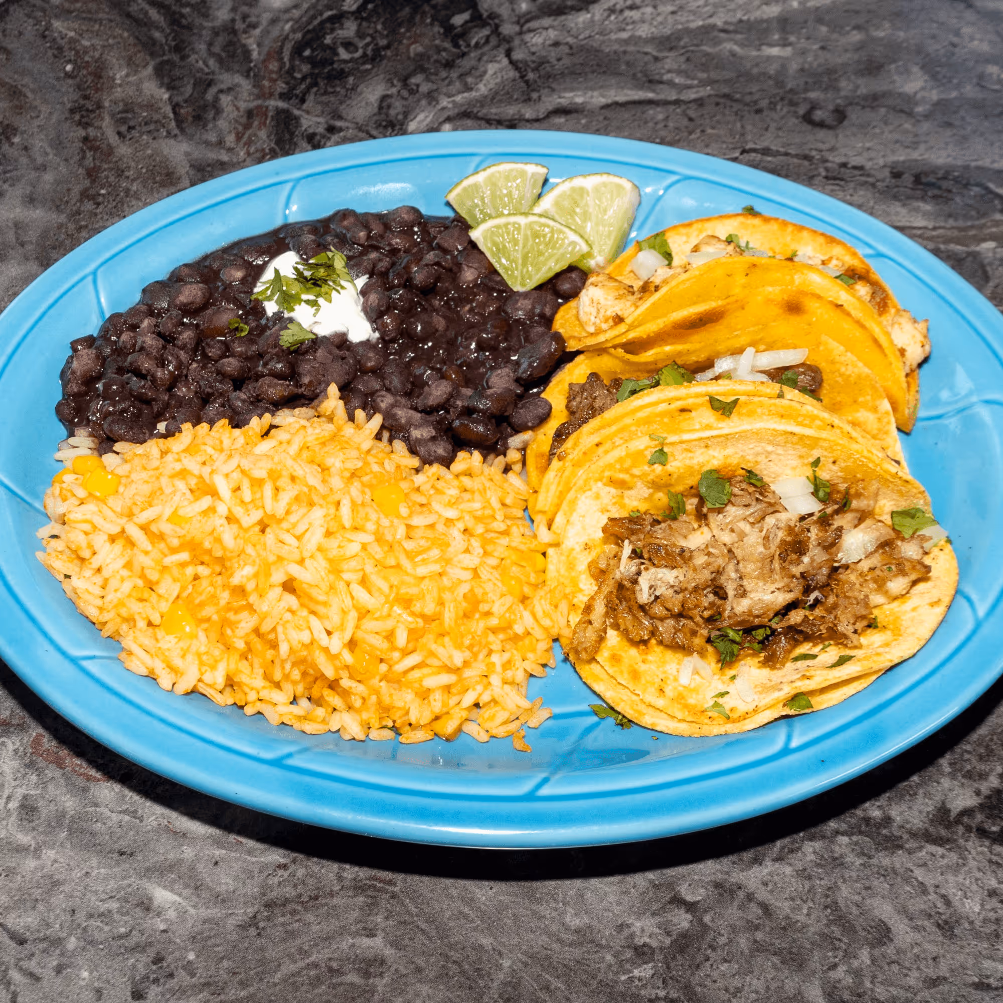 A plate of food with rice, beans, and tacos.