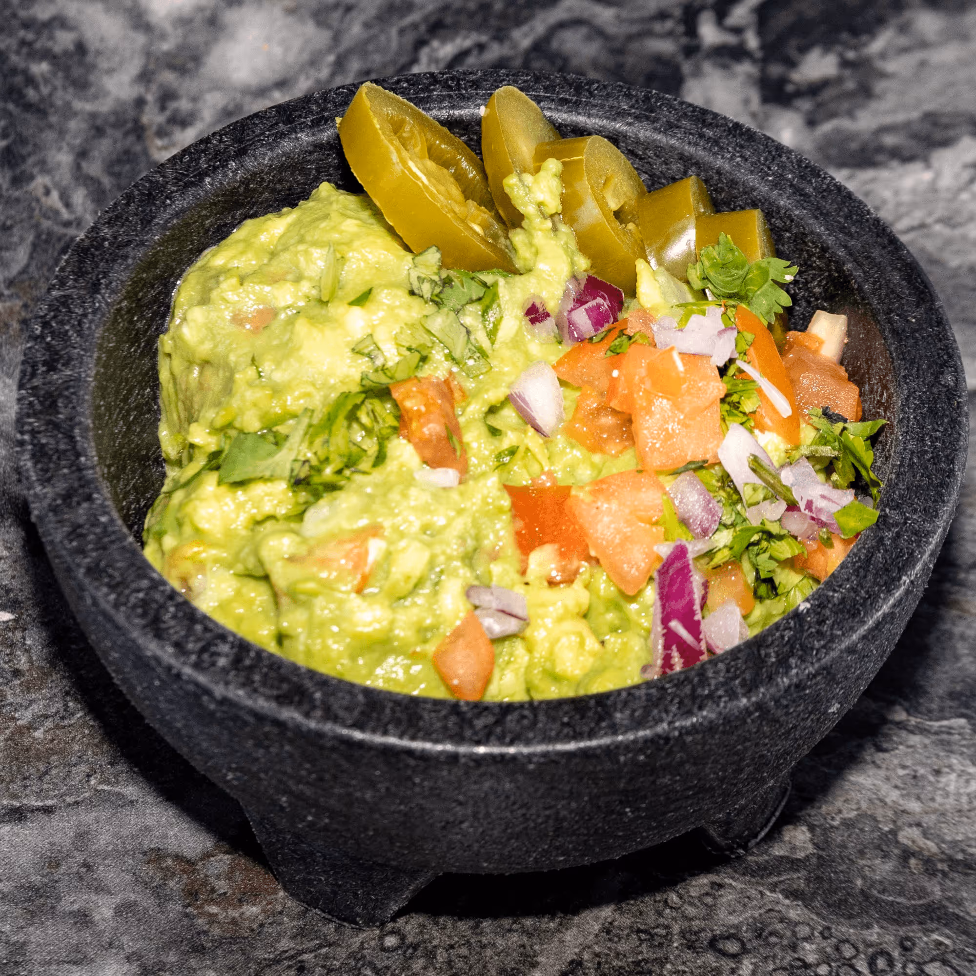 A bowl of food with a green topping.