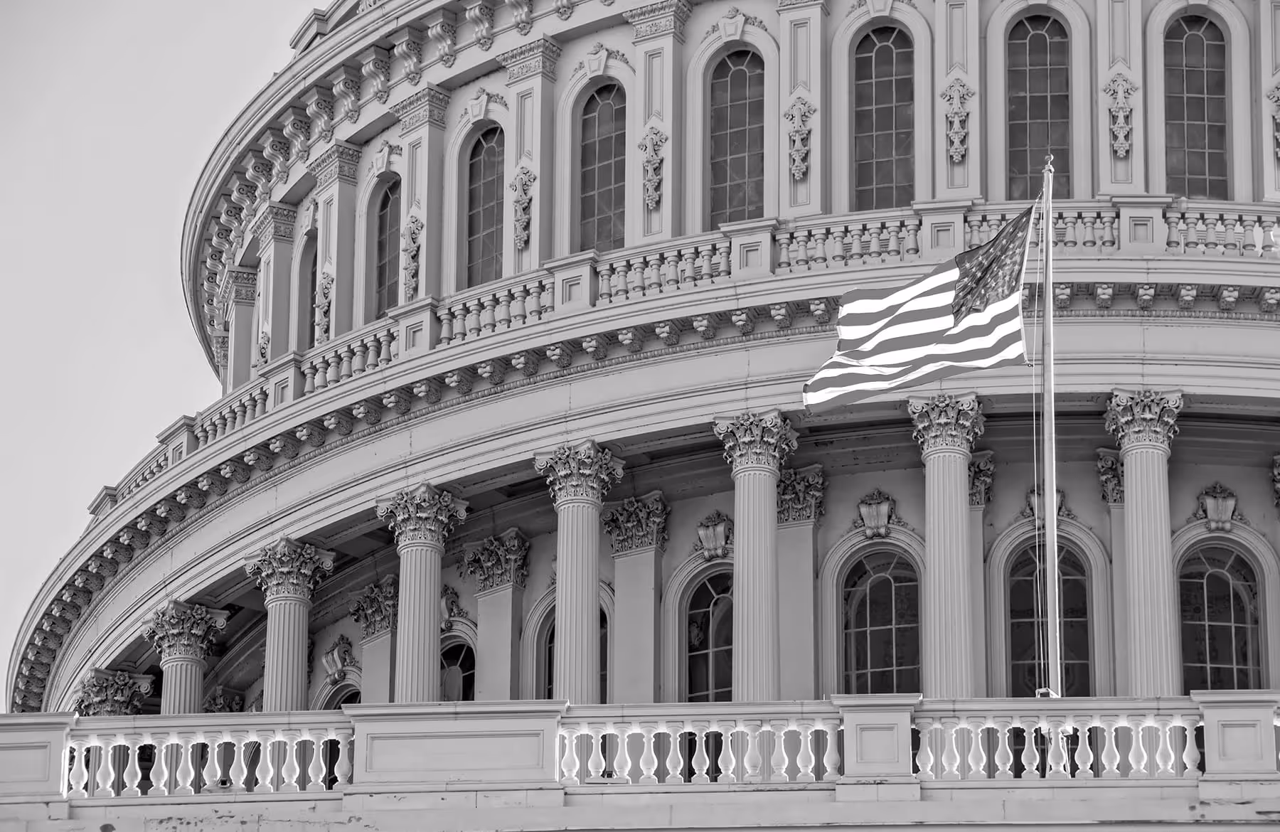 Close-up of the United States Capitol dome with an American flag waving in front.