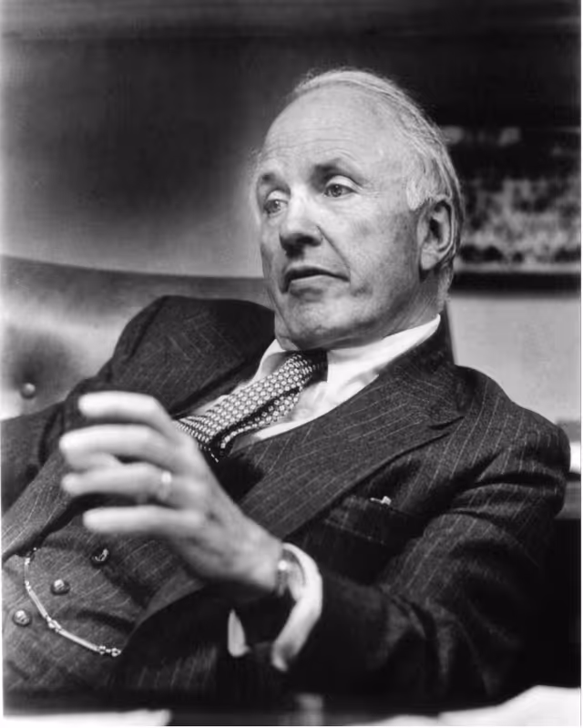Black and white portrait of an older man in a suit, seated and looking to the side with a thoughtful expression.