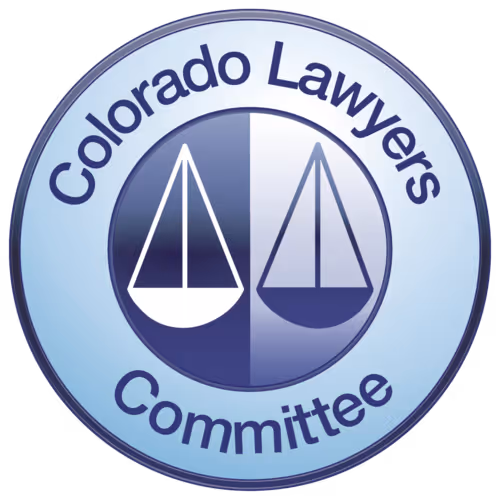 Circular emblem of the Colorado Lawyers Committee with two stylized scales of justice in the center.