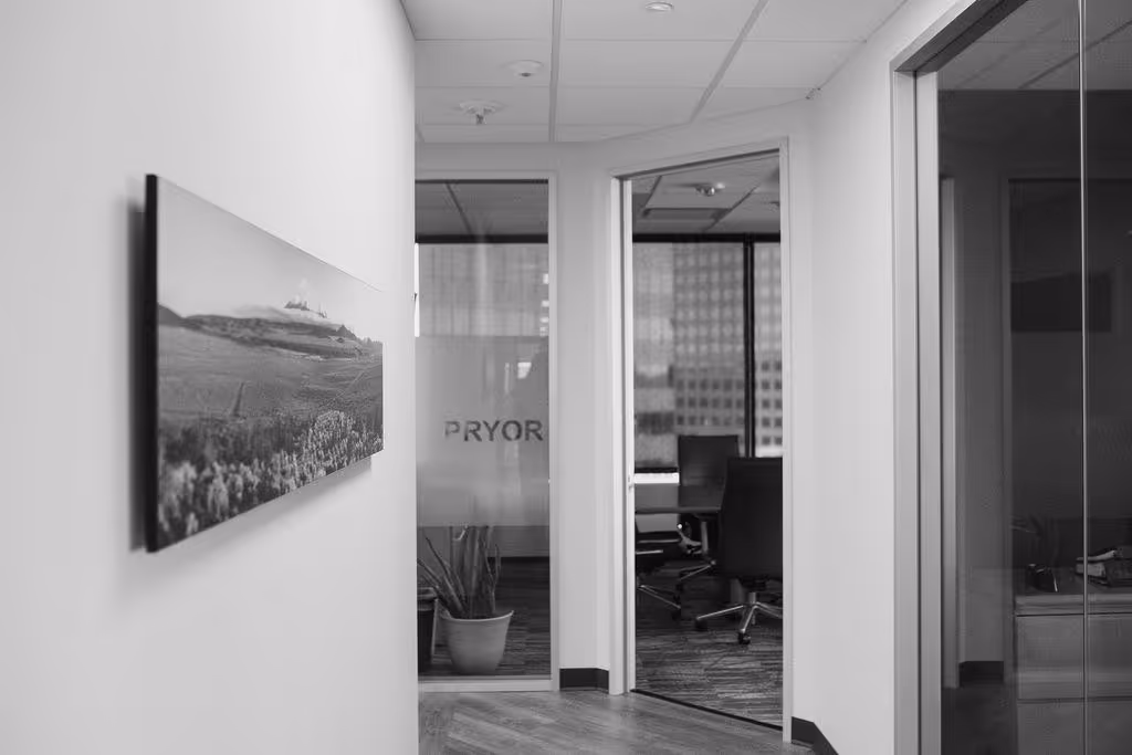 Office hallway with a landscape picture on the left wall, leading to an open glass door with visible office chairs and a frosted glass with the word PRYOR.