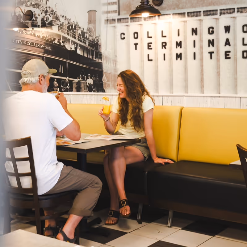 A couple laughing over brunch at Eggsmart Collingwood, thanks to a gift card