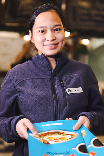 Female server welcomes you with a menu at Eggsmart Collingwood