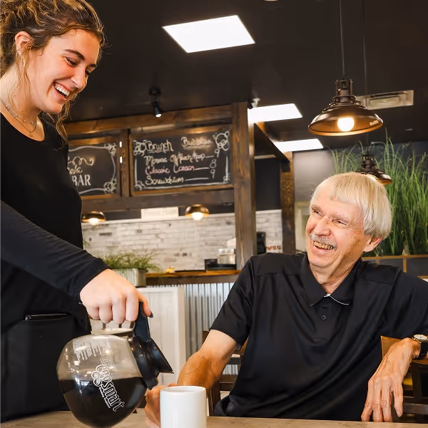 A happy server refilling a happy customer's coffee because our Team Cares at Eggsmart Collingwood