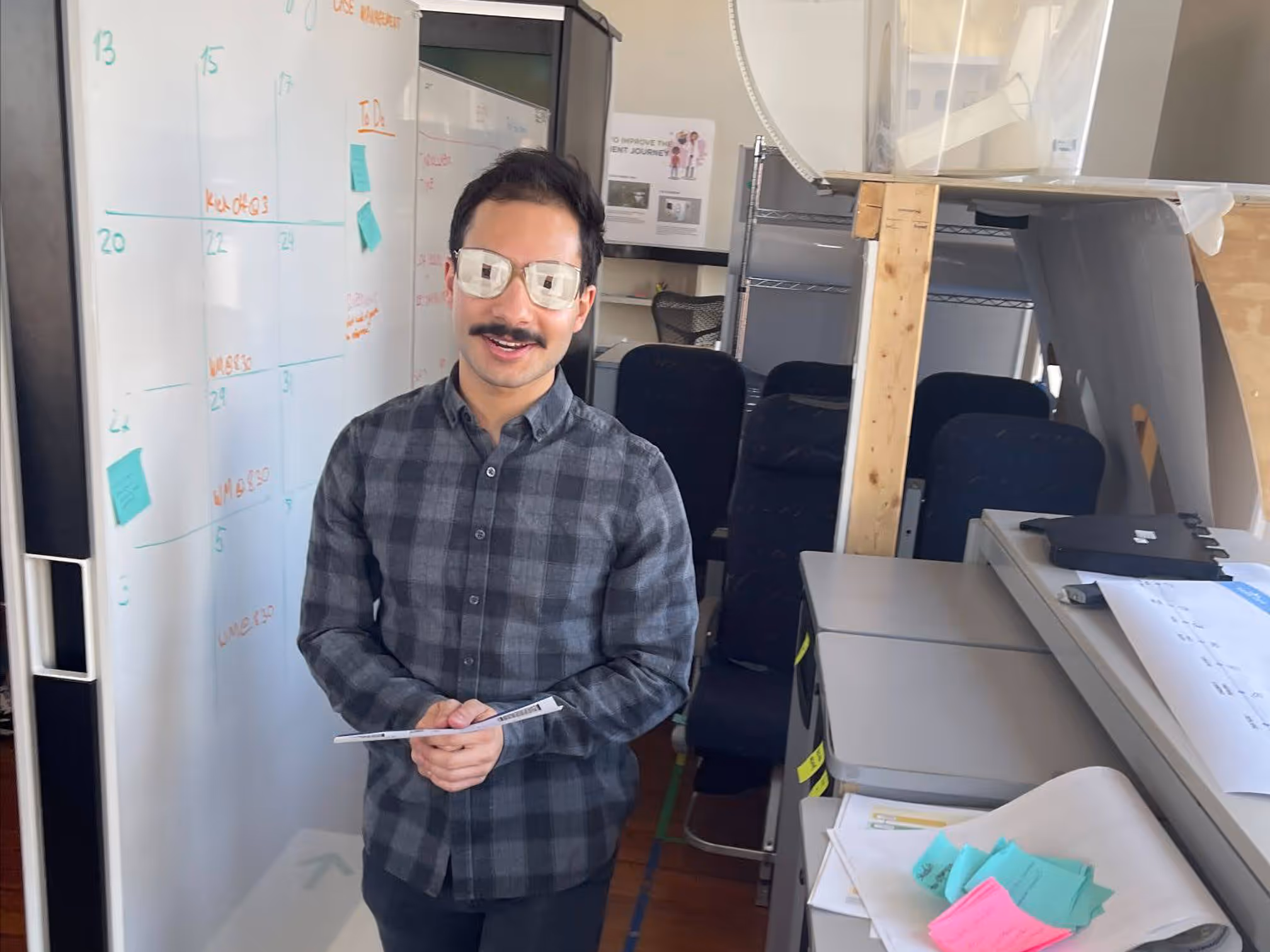 Male student wearing modified glasses to mimic visual impairment while he navigates a model airplane cabin.
