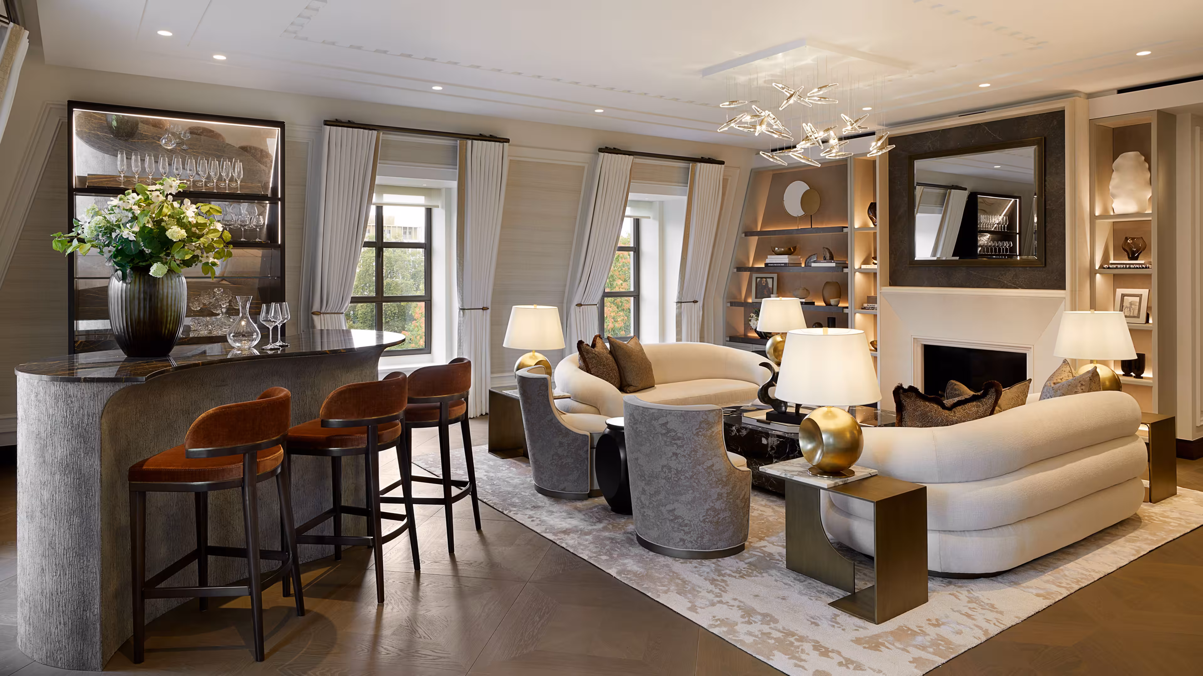 A luxury living room with a pair of white curved sofas, wooden floors and a curved hand build bar area