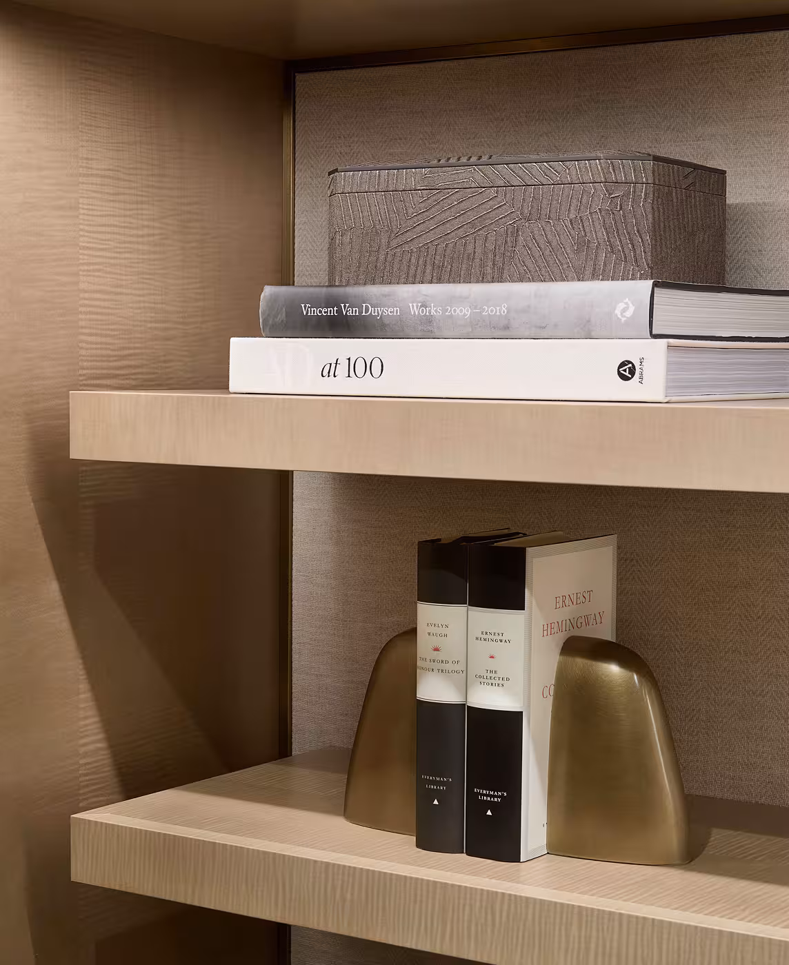 Close up of a bookshelf with four books and gold book stops.