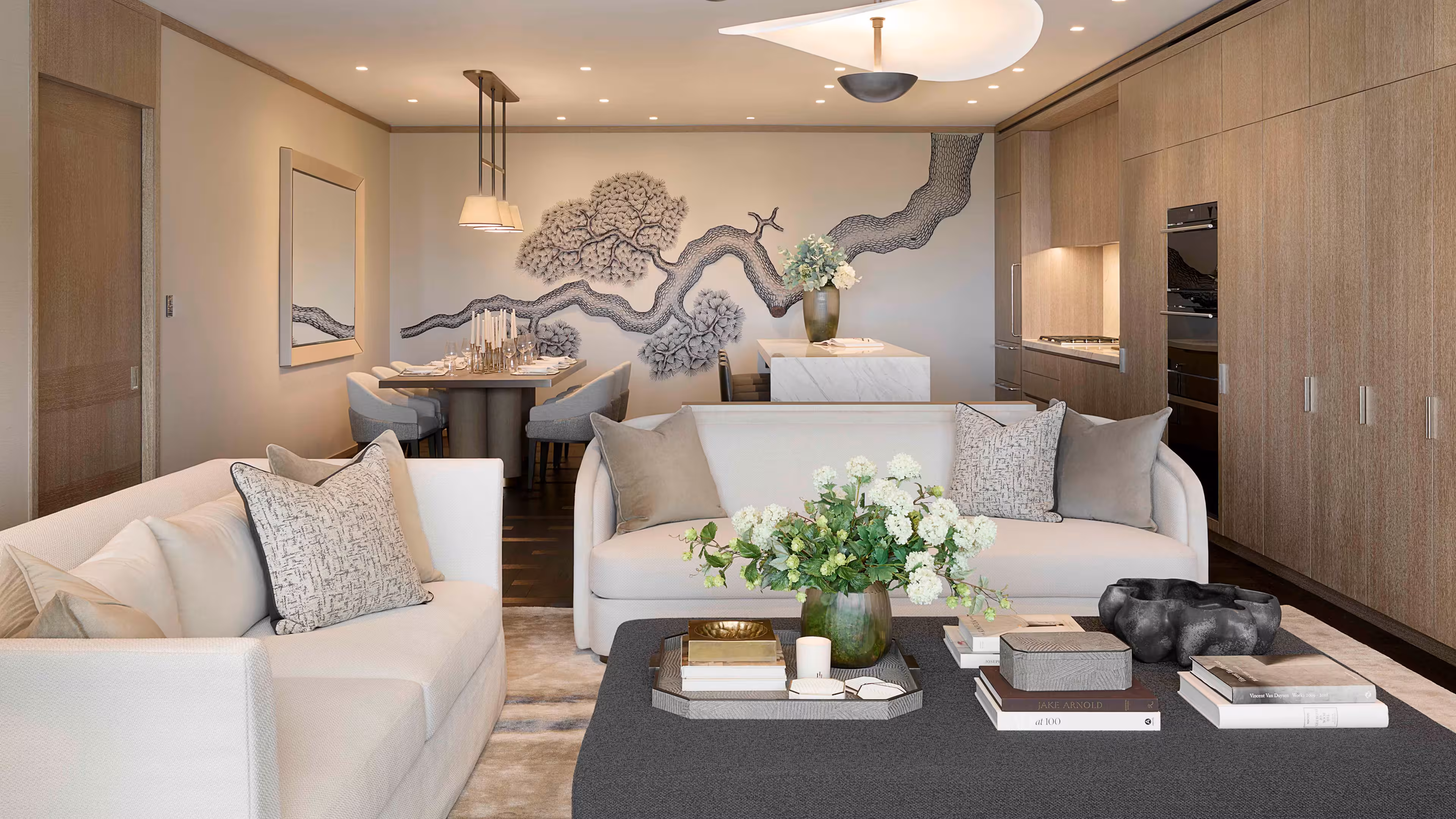 Looking out from the living room into the kitchen area. Light wood coloured, full height kitchen to the right, a sitting table to the left and Japanese artwork painted across the entire back wall in black and white.
