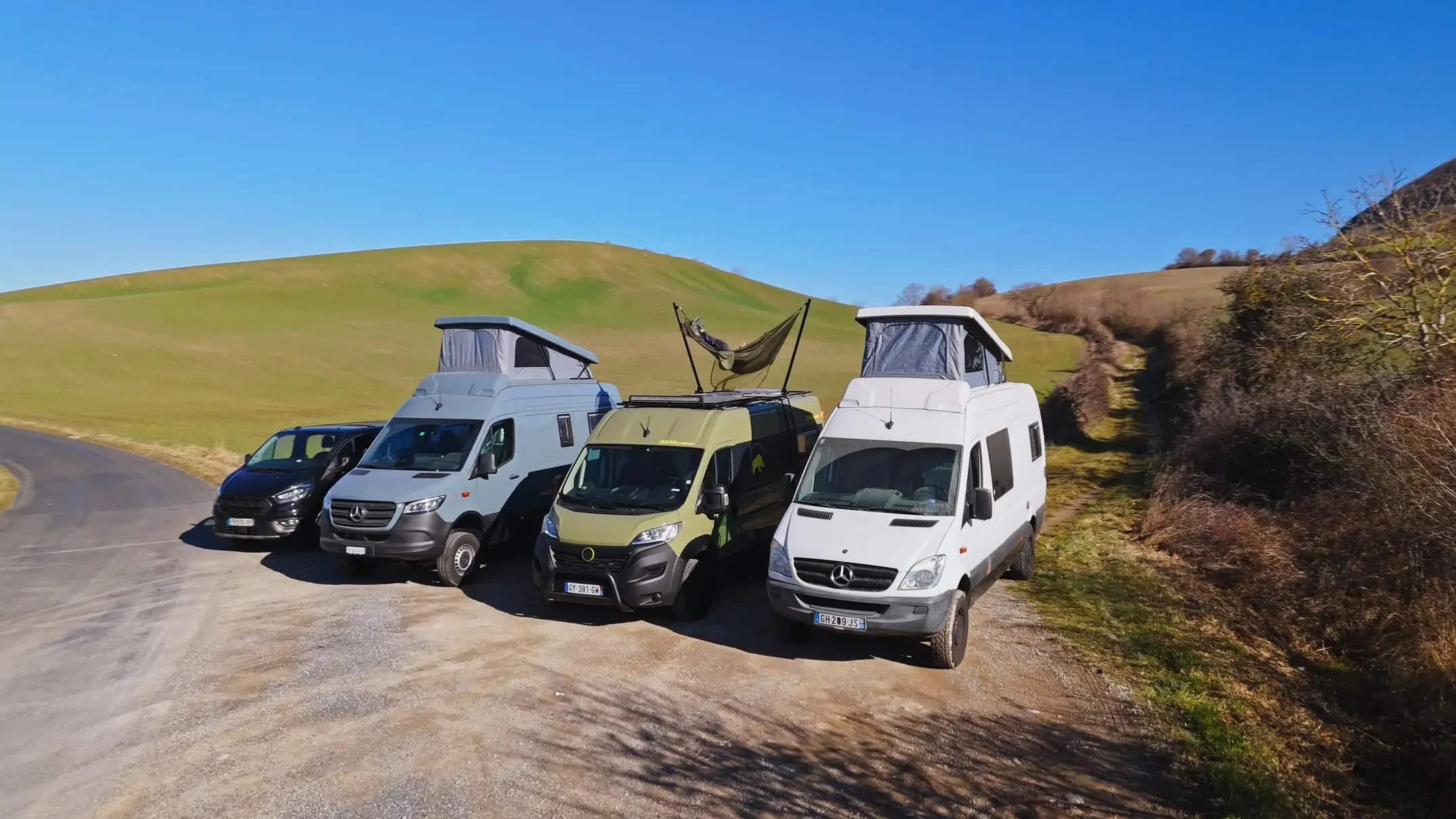plusieurs vans de Javan Campers sont garés en pleine nature