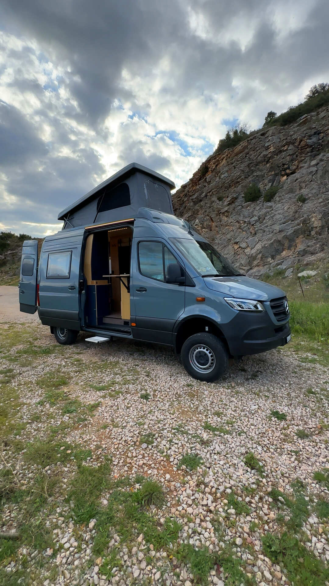 Fourgon Citroën noir aménagé en camping-car avec toit relevable et porte coulissante ouverte montrant un petit évier et un espace cuisine conçu par Javan Campers