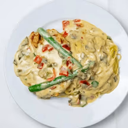 A plate of creamy pasta with chunks of red peppers, mushrooms, and green beans. 