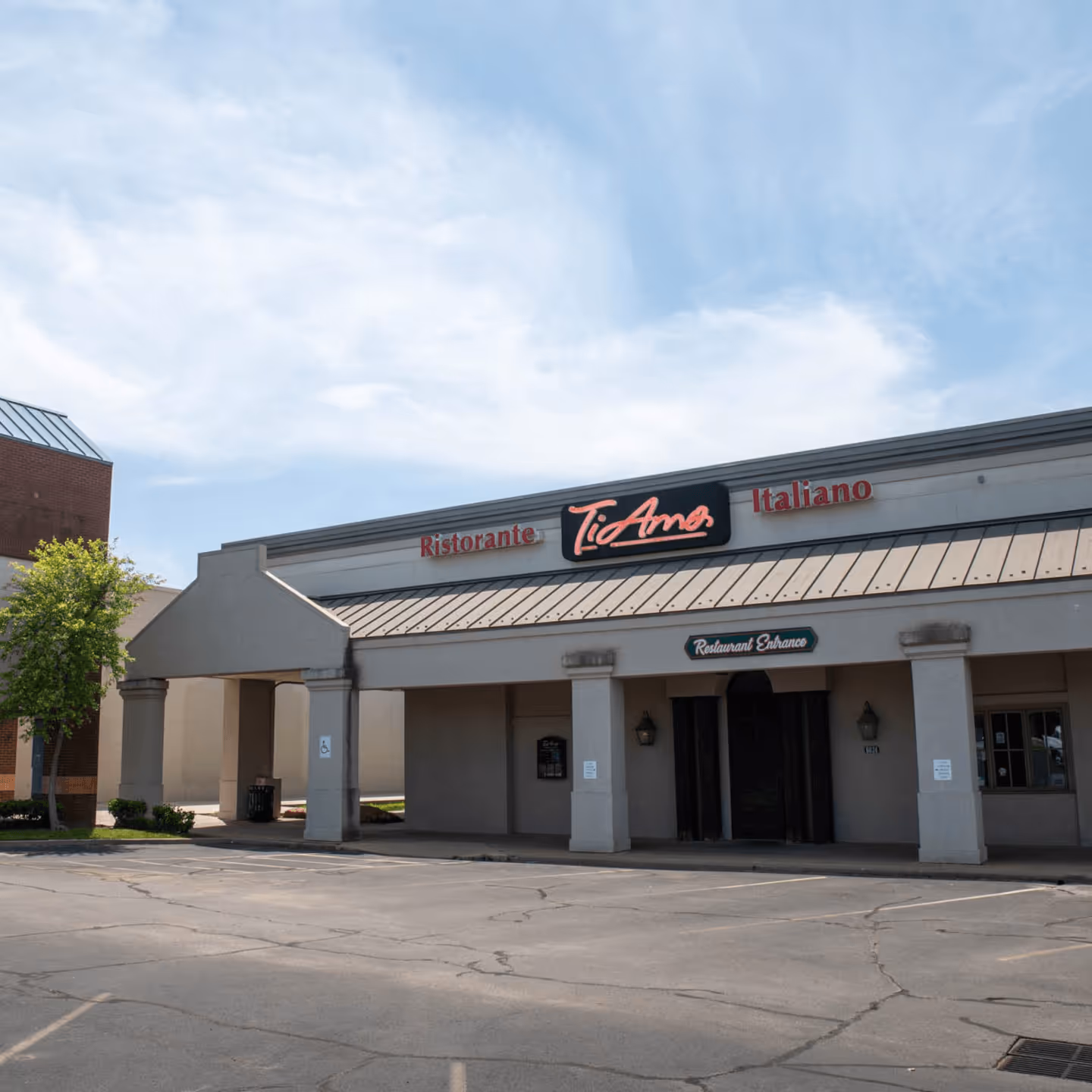 Exterior of an Italian restaurant under a blue sky. Features a spacious parking area and a sign reading "Ristorante Ti Amo Italiano" with a welcoming vibe.