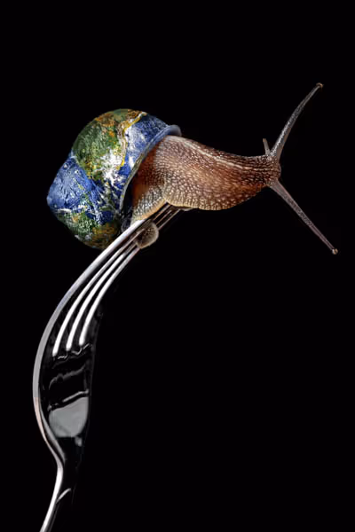 Un escargot posé sur une fourchette avec sa coquille ressemblant à la Terre vue de l'espace, fond noir.