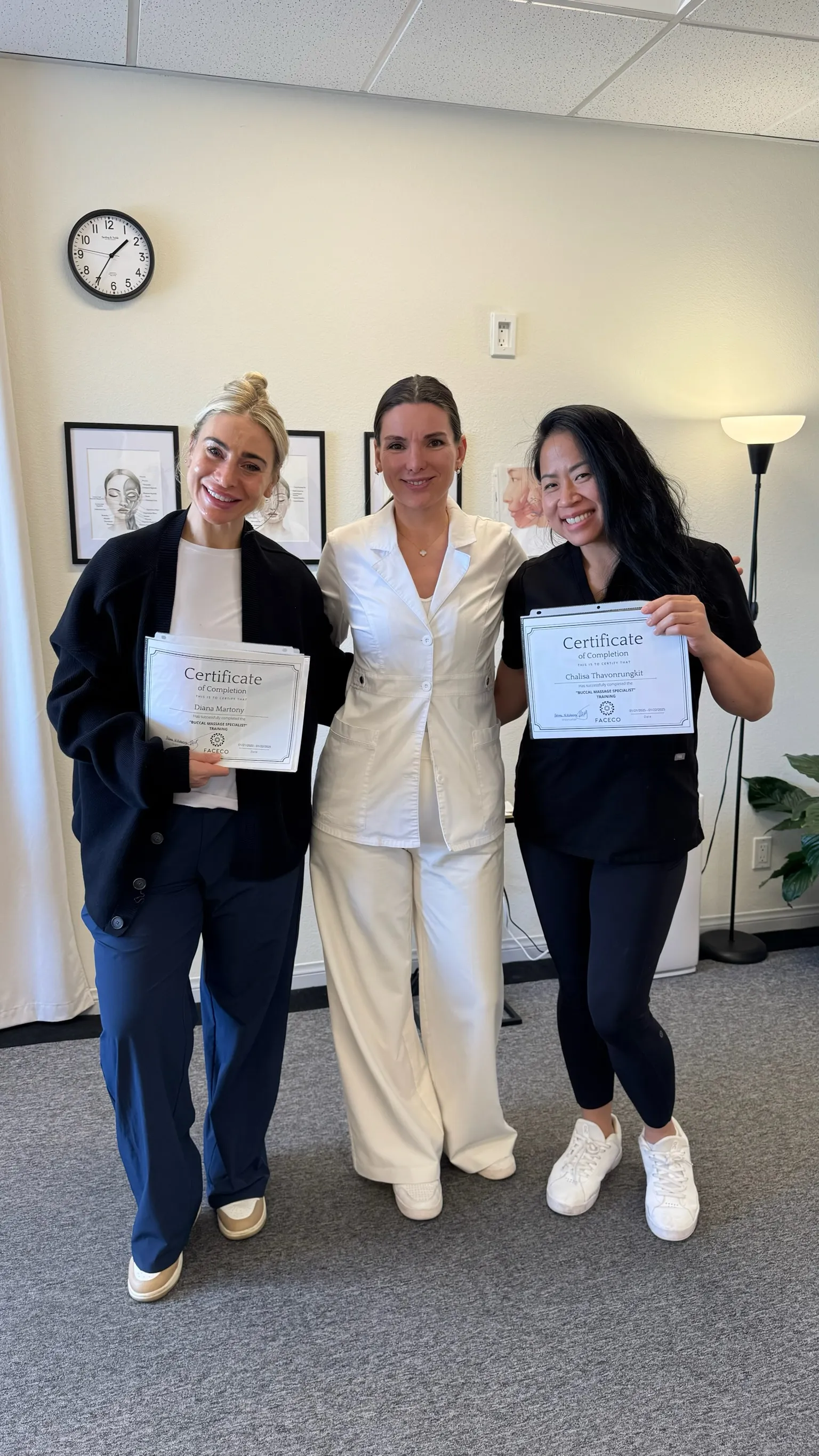 Two women holding certificates of completion for 'Buccal Massage Specialist' training.