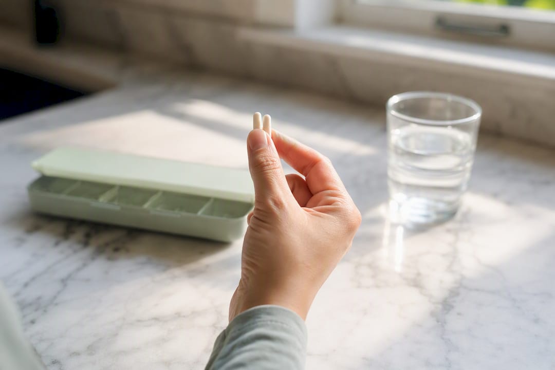 Hand holding two birth control pills