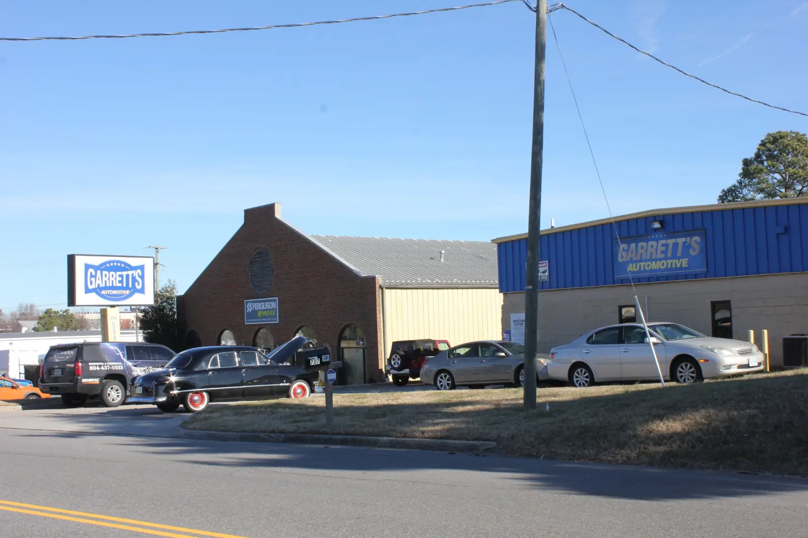 Exterior view of Garrett's Automotive building with several parked cars and a clear blue sky.