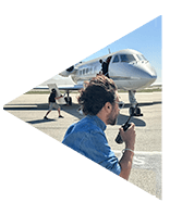 Production studio 1st AD using a walkie on the tarmac in front of a plane