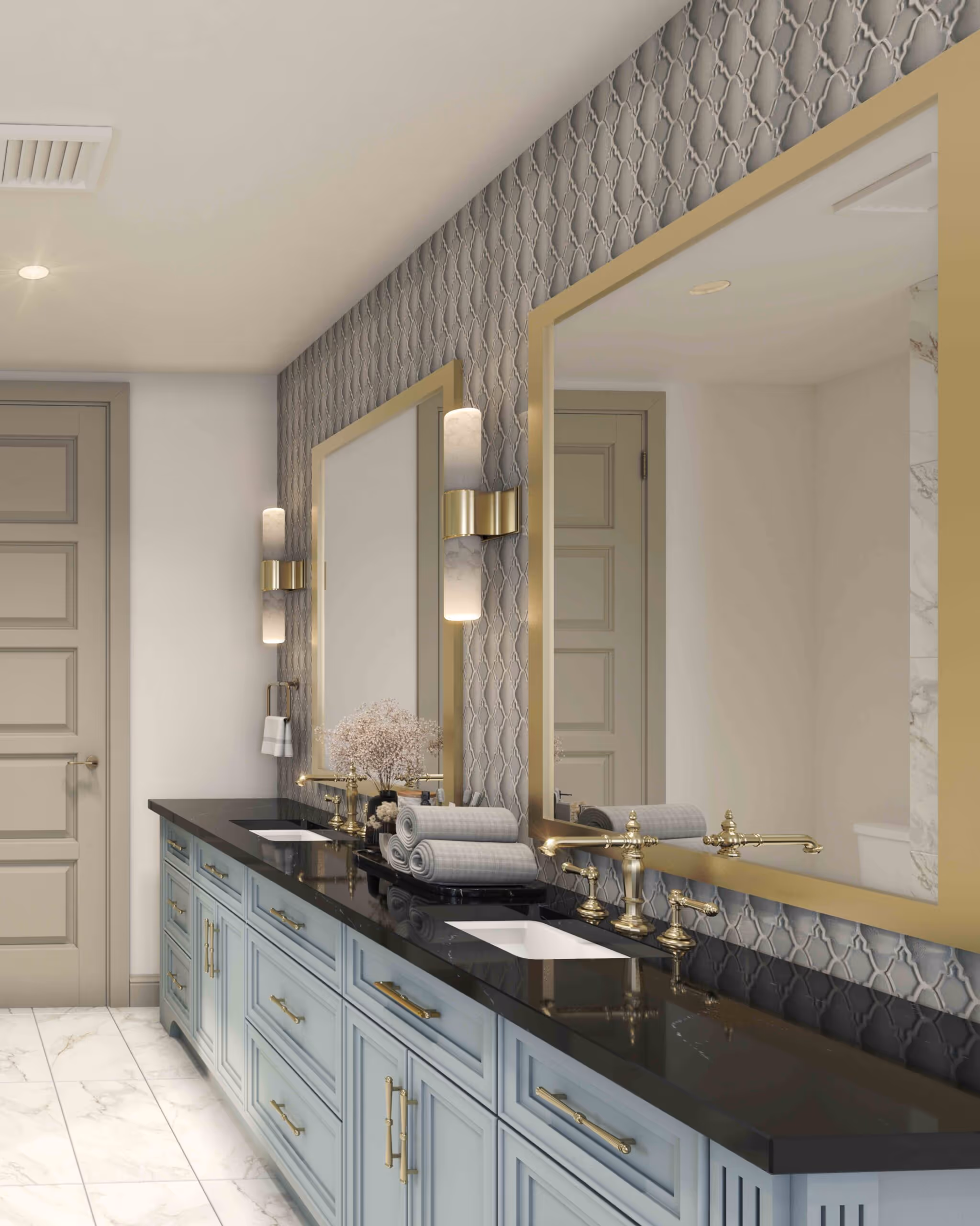 Modern bathroom with double vanity featuring light blue cabinets, black countertop, gold fixtures, large gold-framed mirrors, patterned backsplash, and rolled towels on a tray.