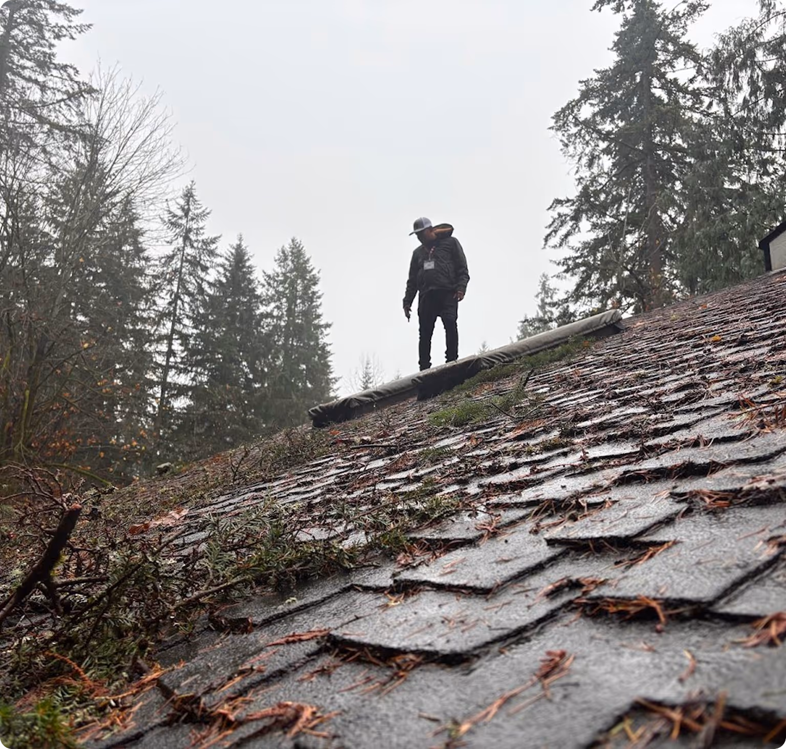 Man standing on roof covered in debris after storm 