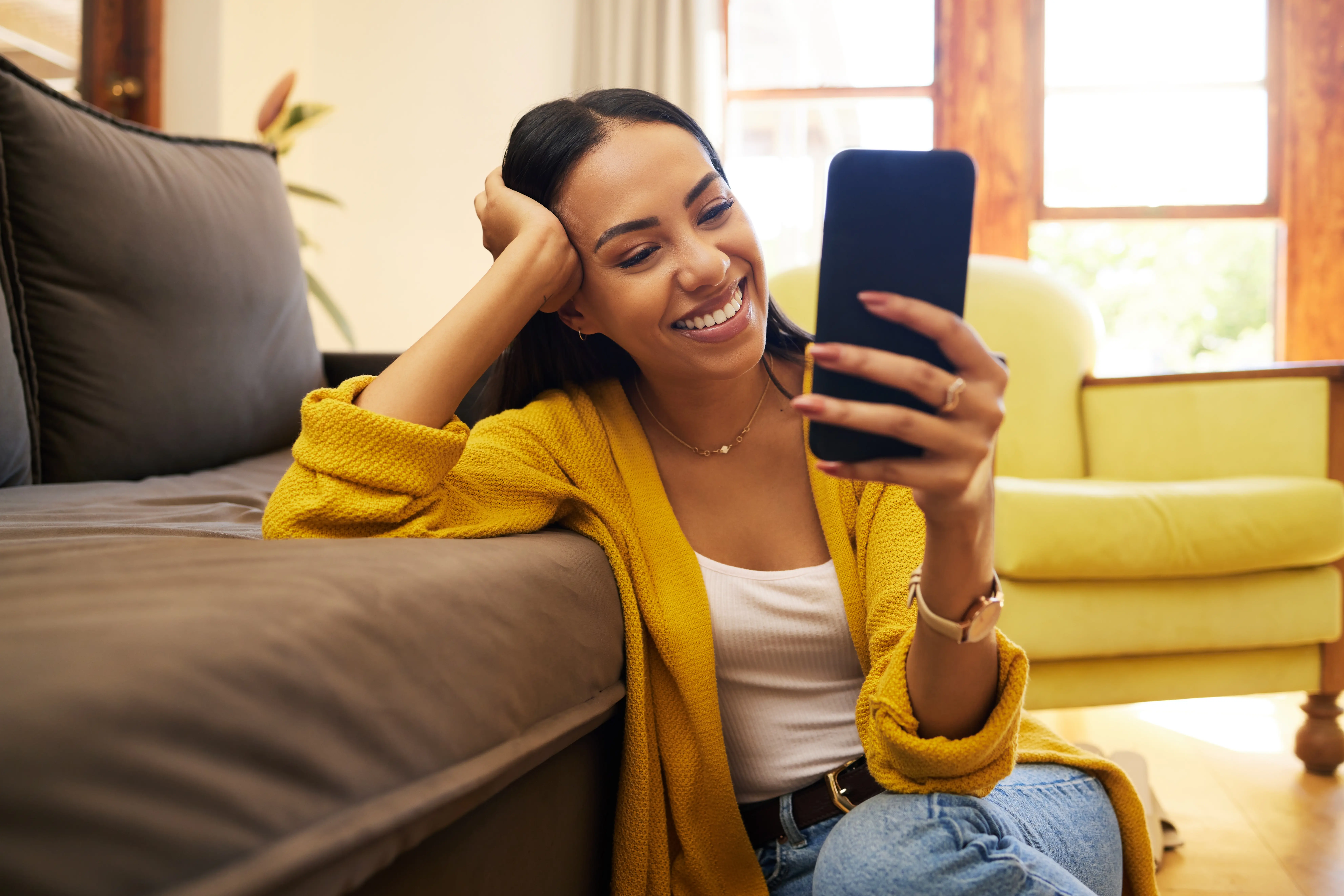 A woman sitting on a couch holding a cell phone.