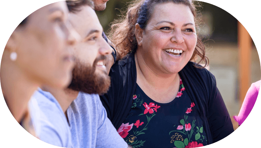 Group of diverse adults smiling and engaged in conversation outdoors.