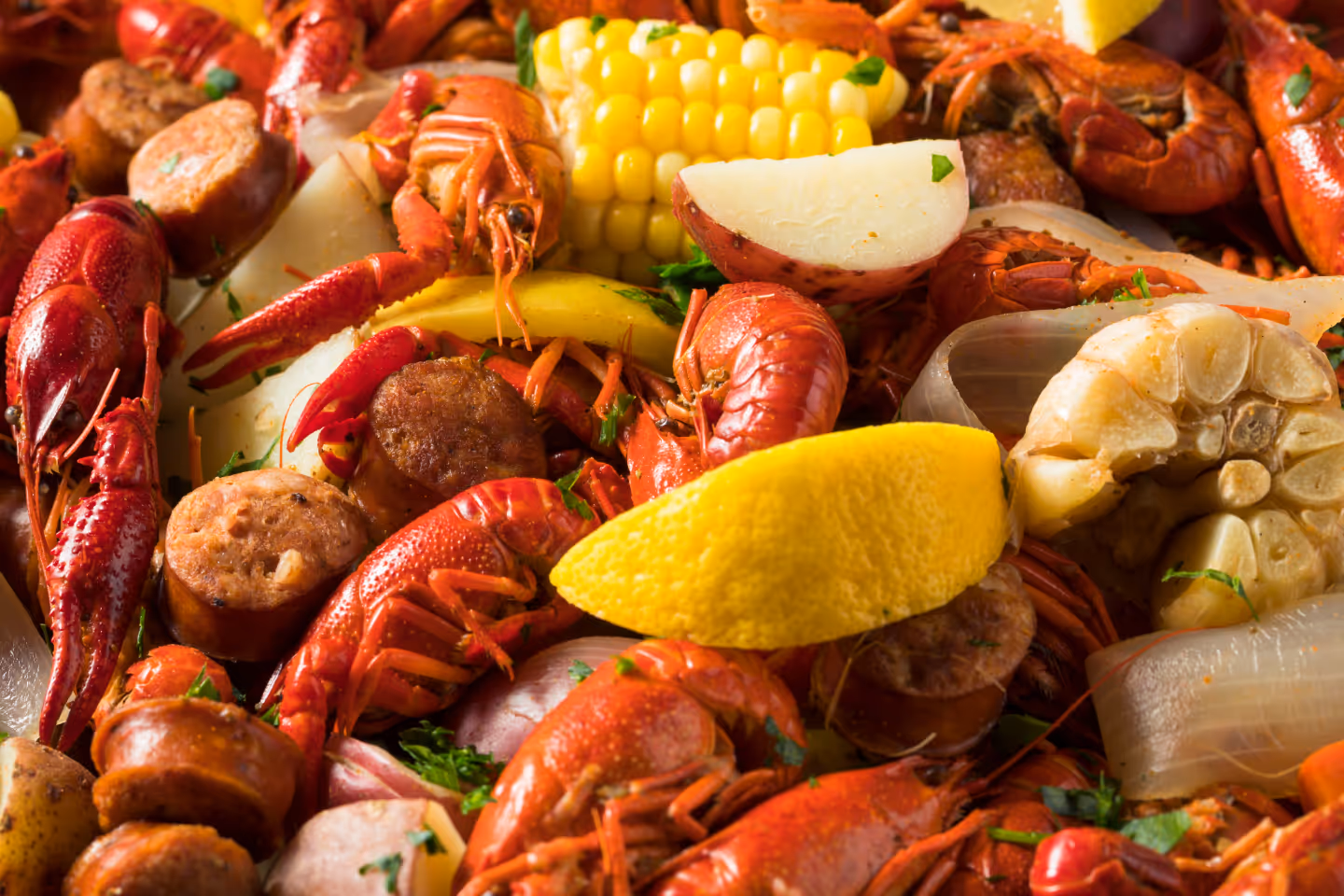 Seafood boil feast with corn, sausage, potatoes, and shellfish.
