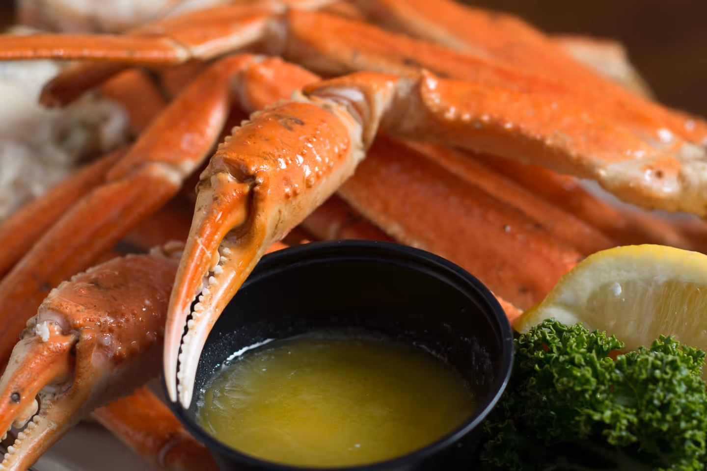 A top-down view of a with a variety of menu items, including a tray of steamed crabs, a plate of sushi rolls, a burger.