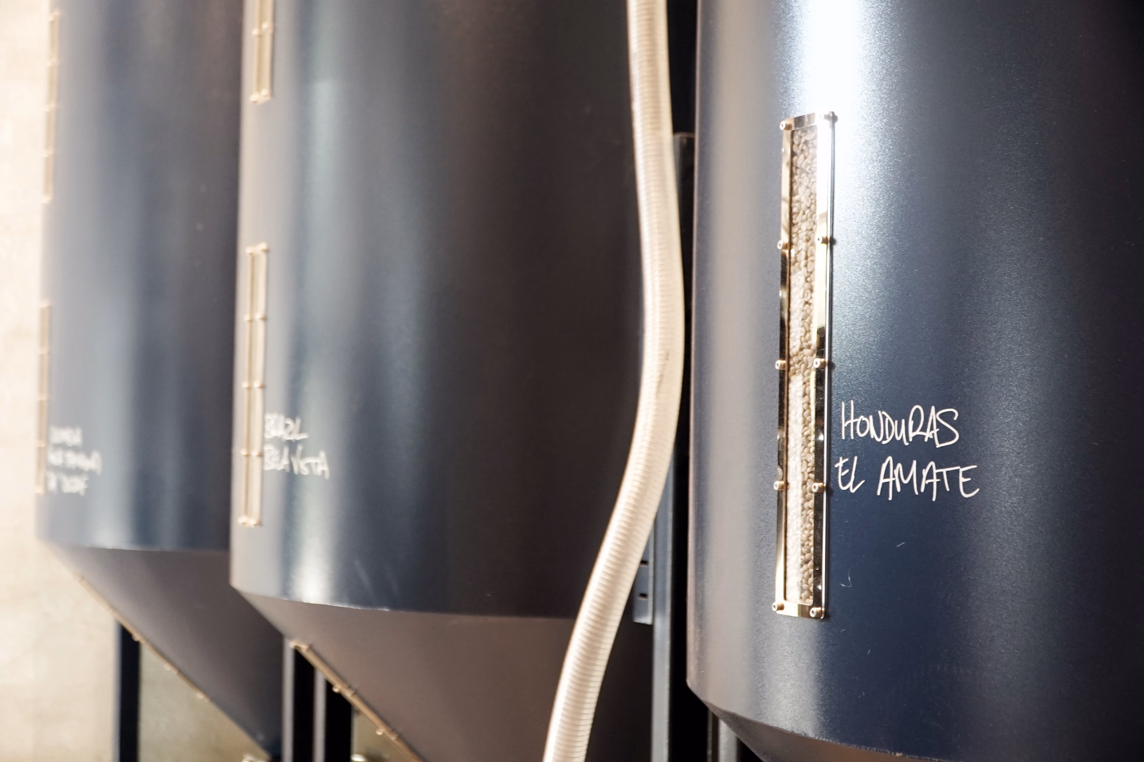 Row of labelled coffee fermentation tanks at the Contraband roastery