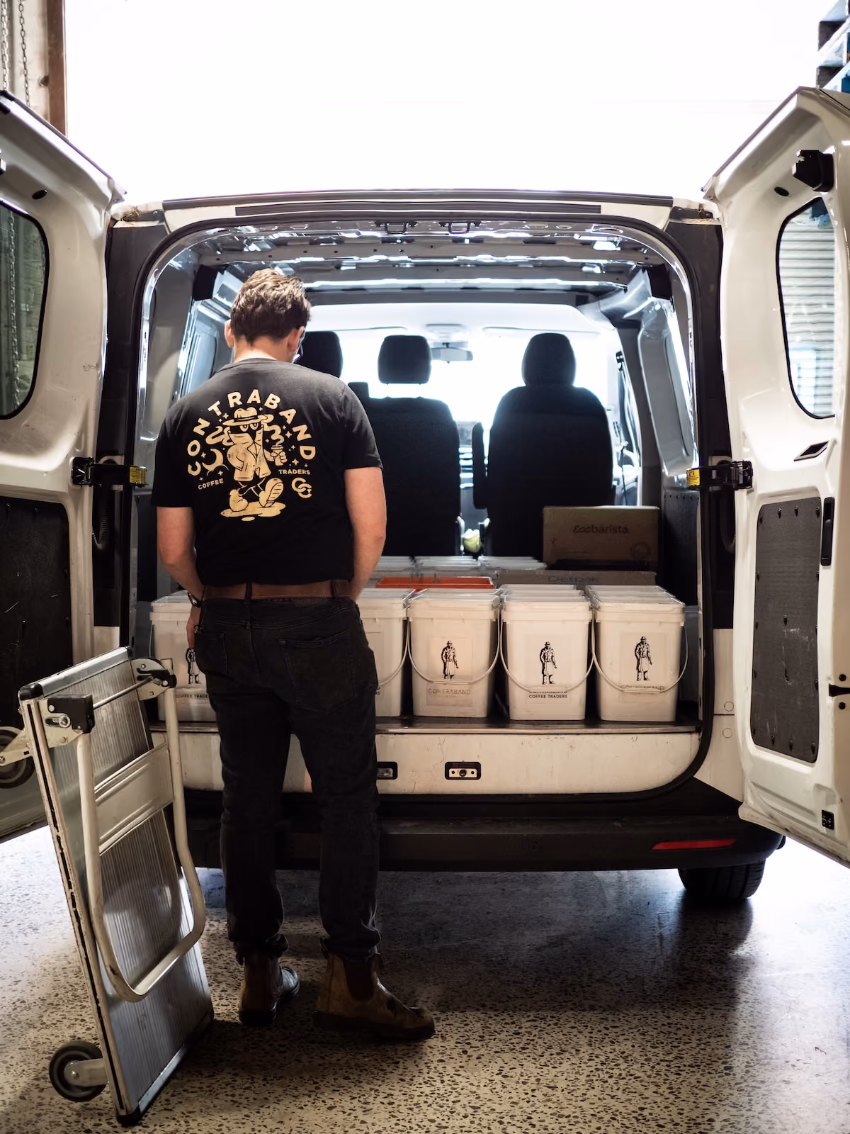 Contraband staff member loading coffee buckets into a delivery van