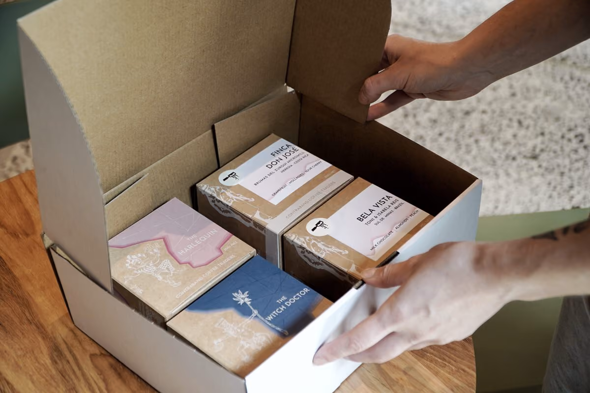 Hands packing a subscription box filled with Contraband coffee bags