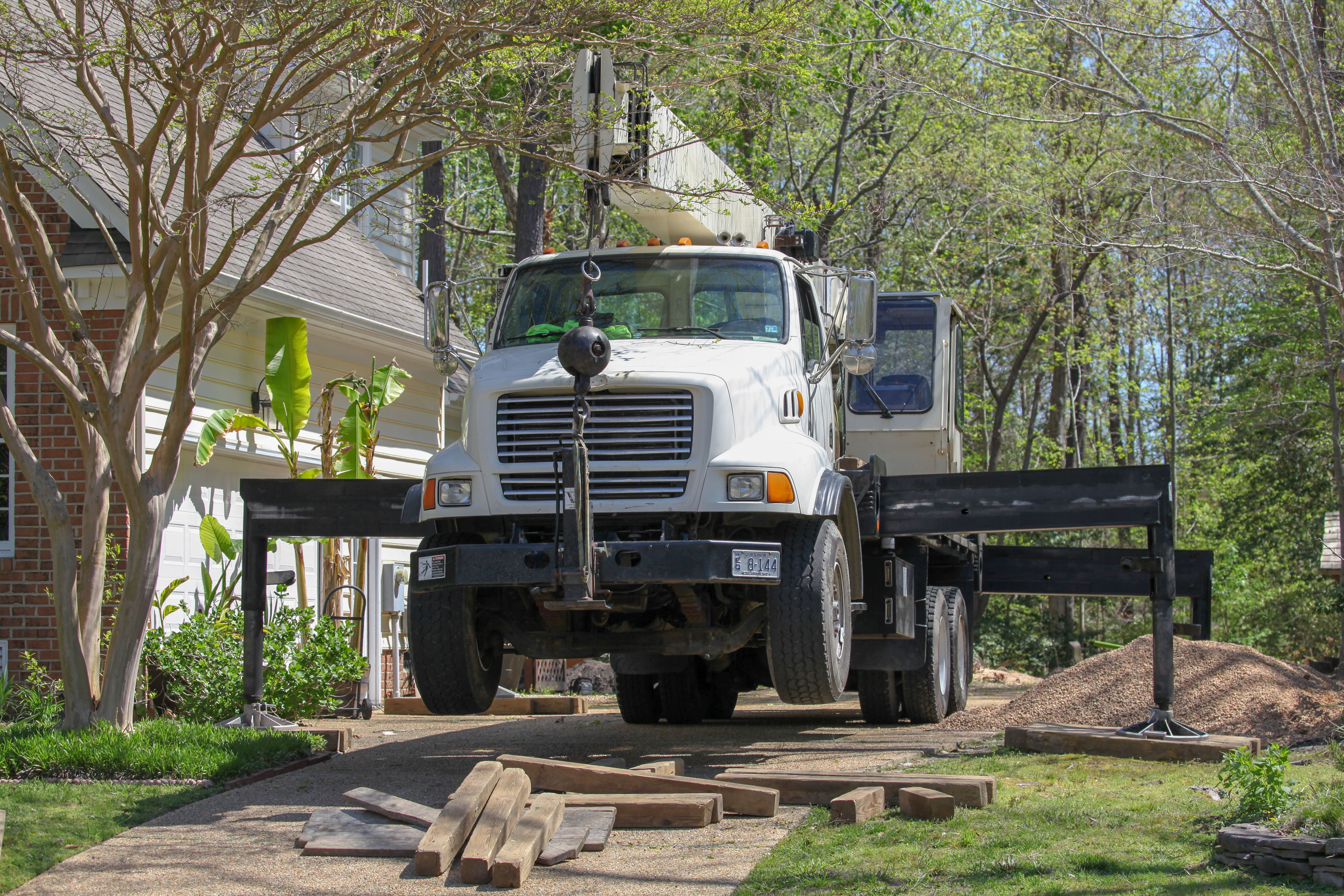 Man wearing a yellow safety helmet and sunglasses secured with climbing gear on a tree branch.