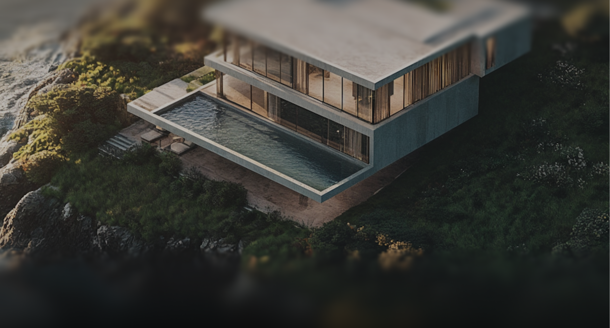 Modern concrete house with large glass windows and an elongated pool extending over rocky greenery near the water.