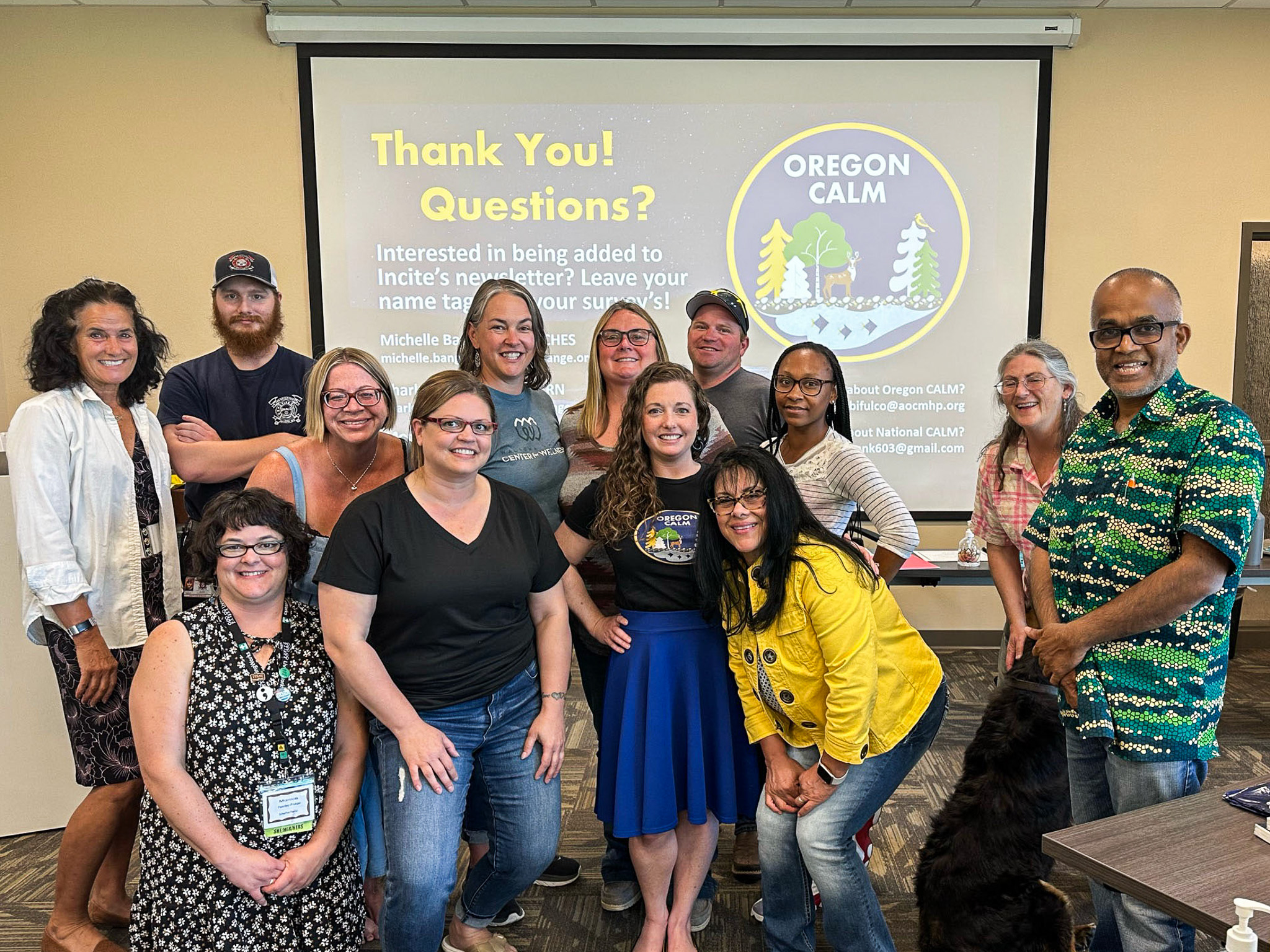 Group of smiling people posing in front of a screen displaying Oregon CALM and a thank you message.