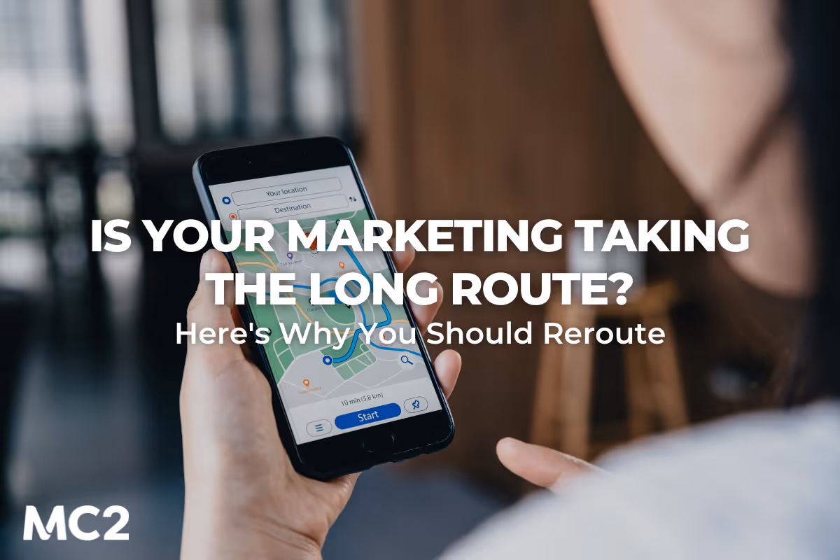Person holding a smartphone displaying a navigation map, with text overlay: 'Is Your Marketing Taking the Long Route? Here's Why You Should Reroute' - MC2 Marketing Solutions