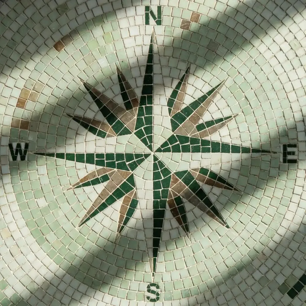 Mosaic compass rose with green and brown directional arrows on a tiled circular background. Perfected Wealth Management Wealth Stewardship