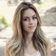 Woman in white sleeveless dress sitting on gray concrete seat during daytime