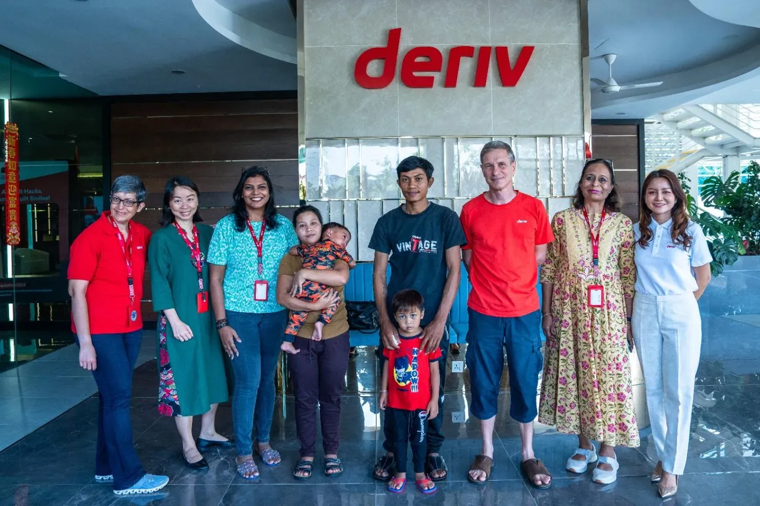Group photo at Deriv with Kwan and his family, along with Deriv employees, celebrating Kwan's cleft lip surgery and recovery journey.
