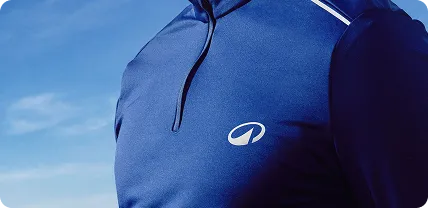 Close-up of a person wearing a navy blue zip-up athletic shirt with a small white logo on the chest against a blue sky background.