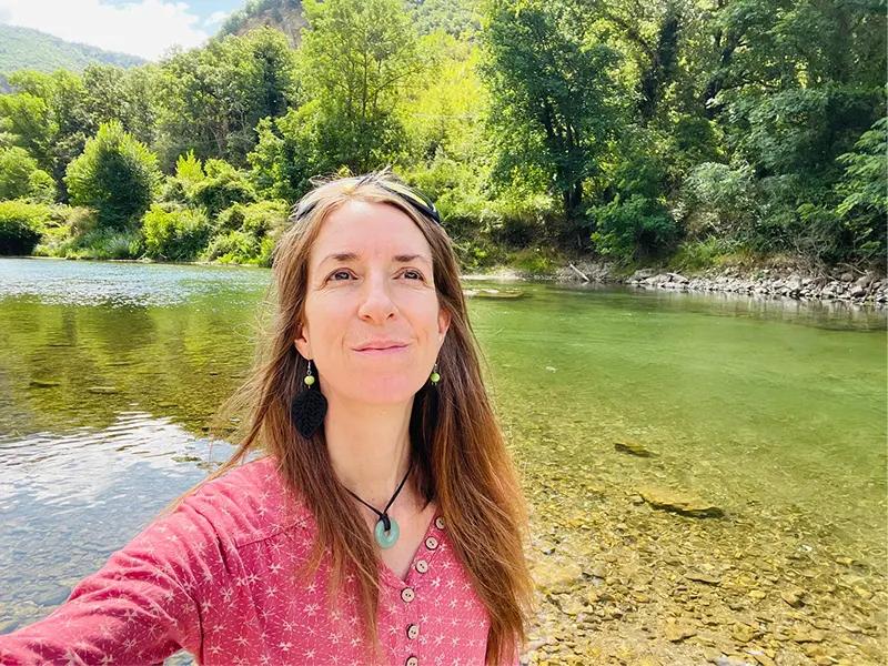 Barbara Edelmann en selfie devant une rivière bordée d'arbres