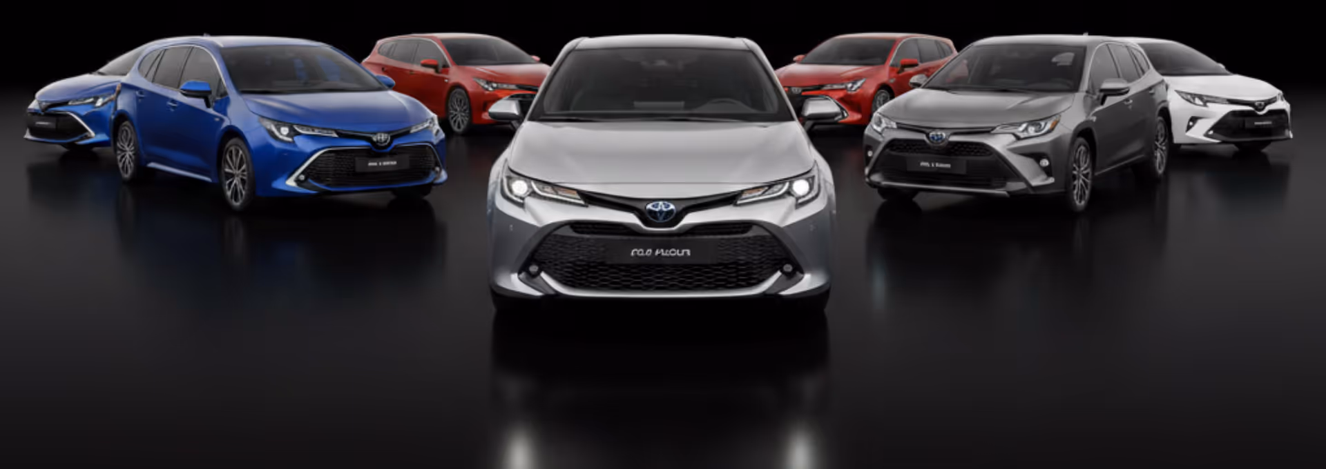 Seven Toyota Corolla cars in various colors arranged in a semi-circle on a reflective black surface.