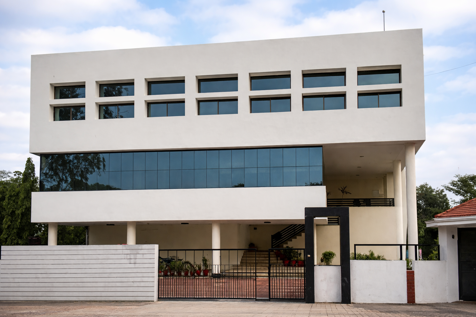 Modern white two-story building with large rectangular windows and a gated entrance.