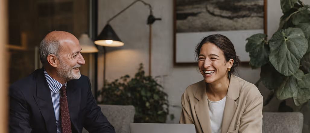 Elderly person and woman sitting at a table laughing and chatting