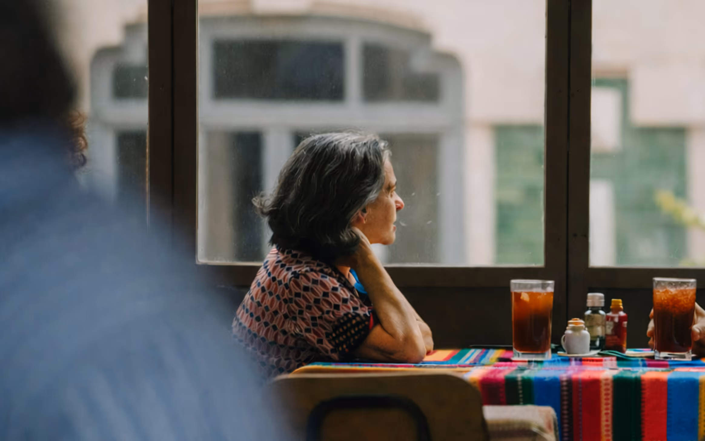 elderly woman sitting at a table looking outside