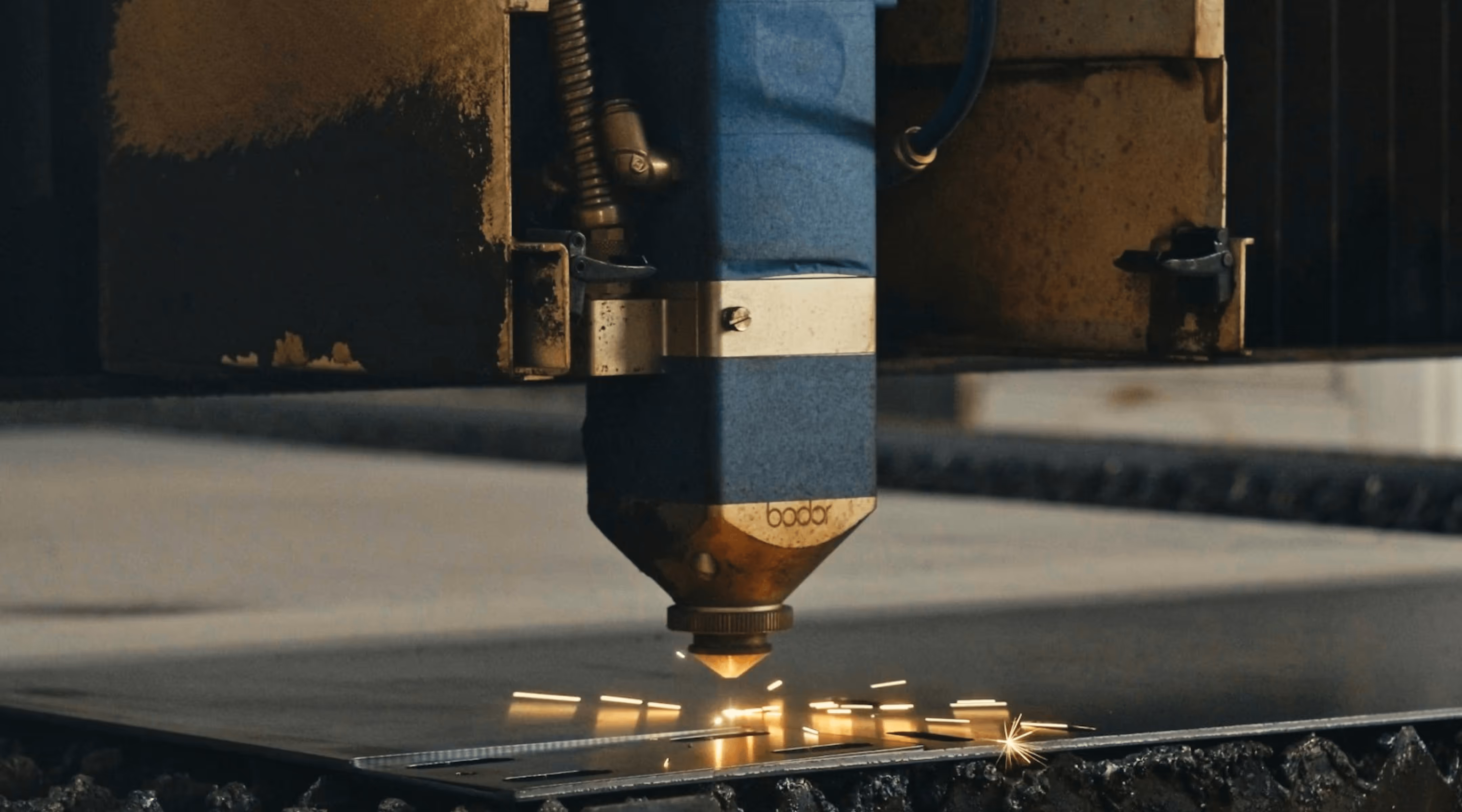 Close-up of a Bodor laser cutting machine engraving sparks on a metal sheet.